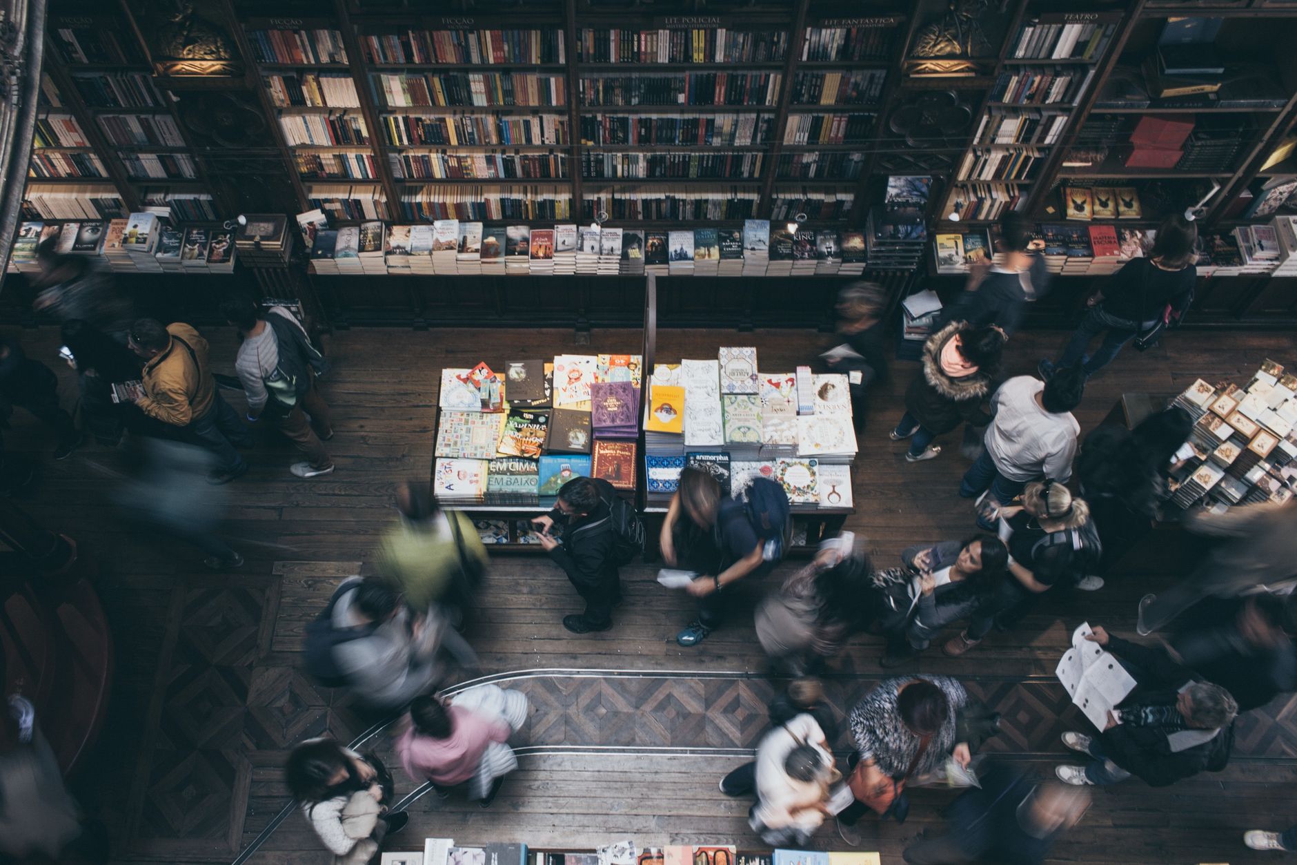 Busy bookstore scene in Porto, Portugal, with people browsing shelves and blurred motion capturing the dynamic atmosphere.